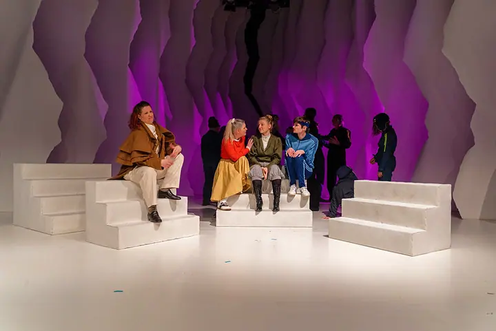 Gebärden der Geschichte mit Ensemble auf Treppen vor violett beleuchteter Bühnenlandschaft